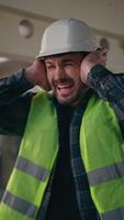 Caucasian builder worker man guy male handyman engineer architect in hardhat employee closing ears with hands industrial loud explosion in construction factory hiding from demolition building noise video