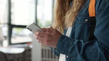 Closeup of male student hands typing on smartphone in university hallway unrecognizable man guy texting message mobile phone browsing online content indoors communication education modern technology video