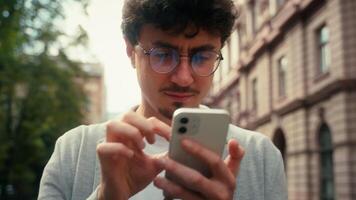 Pensive traveler tourist confused Hispanic man guy male using mobile phone map navigation walking in city going to location searching address navigator go at street application smartphone location video