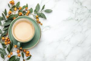 Overhead View of Coffee Cup with Yellow Berries and Green Leaves on Marble Surface photo