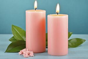 Burning Pink Candles with Green Leaves on Teal Surface photo