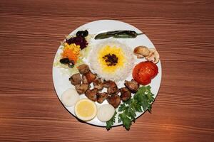 Turkish kebab plate with rice and salad on wooden background. Retro flash food photography photo