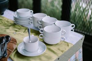 Neatly Stacked White Coffee Cups and Saucers on a Buffet Table photo