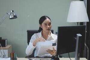A woman is sitting at a desk with a piece of paper photo