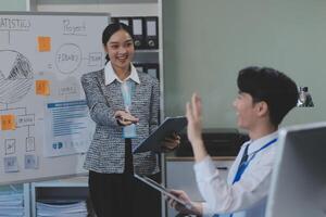 A woman in a business suit is talking to a man in front of a whiteboard photo