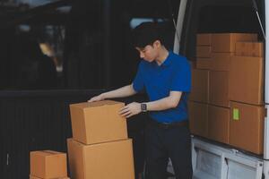 A man in blue shirt and blue pants is loading boxes into a van photo