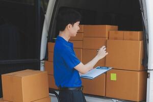A man in a blue shirt is standing next to a van with boxes photo