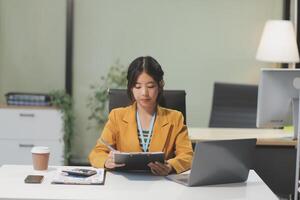 A woman in a business suit is sitting at a desk with a laptop photo