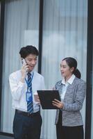 Two business people standing next to each other talking on a cell phone photo