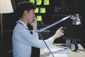 A man sitting at a desk with a computer and a phone photo