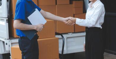 A man and woman shaking hands in front of a truck photo