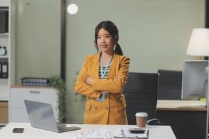 Asian businesswoman standing in front of her desk photo