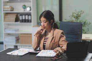 A woman sitting at a desk with a laptop and papers photo