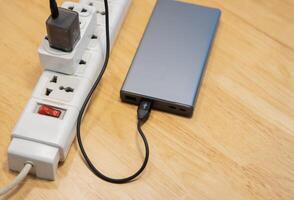 Top view of the power bank is charging with multiple socket on wooden desk. photo
