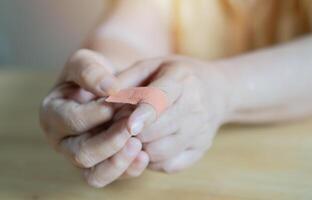 Shot of woman wrapping her injured index finger with a plaster bandage at home. photo