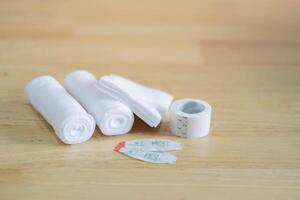 Gauze, ace bandage, tape, bactericidal patches and bandages shot on wooden background. photo