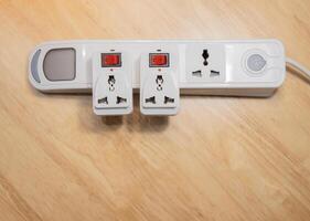 Electrical Extension cord with different adapters on wooden background. Top view. photo