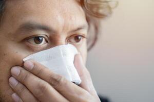 Close-up of men pains, nose and gauze bandage on his nose and looking forward with copy space. photo