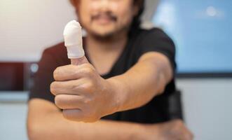 Men's hand has been injured by the accident and showing thumb up with a bandage. photo