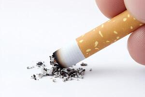 Fingers gripping a burning cigarette with ash cascading onto a white background, illustrating the themes of smoking, addiction, and the associated health risks photo