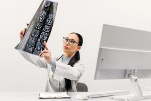 A female doctor analyzes an MRI or CT X-ray image of a patient in a radiology center at a computer. The concept of modern diagnostic methods. White background photo