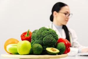 Shot of beautiful smart nutritionist woman working with computer while taking notes. Nutritionist consultation. Fresh vegetables and fruits are on the table. The concept of healthy eating photo