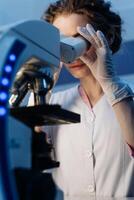 Scientist using microscope in laboratory. Close-up of a researcher hands adjusting a modern microscope in a lab setting. Serious concentrated female microbiologist. Science concept. Vertical photo