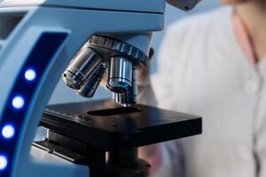 Scientist using microscope in laboratory, making medical testing and research, close-up. Biotechnology research in science lab. Microbiology equipment. Chemistry scientific concept. Ads, copy space photo