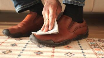 Cleaning brown shoes with a cloth on a carpeted floor video