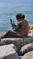 Enjoying a peaceful moment by the water while using a smartphone video