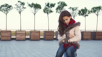 A sweet girl sits in the middle of the street, looking sad and contemplative video