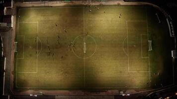 An Aerial View Capturing a Beautifully WellLit Soccer Field at Night with Energetic Players Engaged in Action on the Grass, Showcasing the Excitement and Competition of the Game Under Bright Lights video