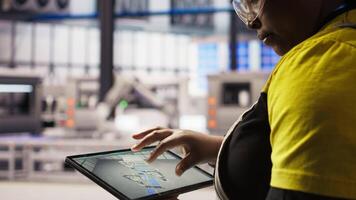 Close up of technician using tablet CAD app to design smart factory layouts. Specialist using simulation application on device to simulate and optimize production systems in automated plant, camera A video