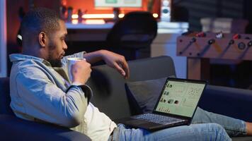 schwarz männlich Händler Überwachung Lager Markt echt Zeit Änderungen auf Laptop, investieren Mittel mit das Tor zu Boost Verdienste. konzentriert jung Kerl studieren wirtschaftlich Werte zum global Förderung. Kamera b. video