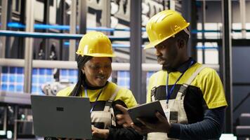 Solar panels factory engineering team analyzes performance data on laptop to predict gear failures. Teamworking photovoltaics plant colleagues following maintenance procedures, camera B video