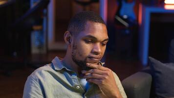 Black teleworker thinking about ways to improve his productivity, looking for new ideas for personal and professional development. Working from home on laptop, networking. Camera B. video