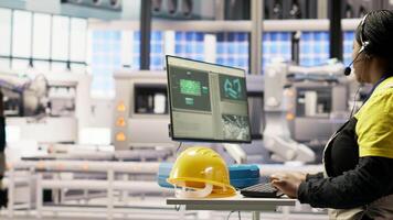 Automated manufacturing plant specialist analyzing live production data, using headset mic to communicate insights to engineers about robotic arms, conveyor belts and photovoltaic systems, camera B video