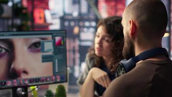 Graphic designer and photographer collaborate in a modern studio, using photo editing software and tools on PC. Team does retouching with advanced image adjustment tools. Camera B. video