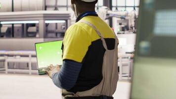Smart factory mechanic testing automated systems using isolated screen laptop, doing maintenance. Industry 4.0 plant serviceman inspecting equipment using mockup notebook to identify errors, camera B video