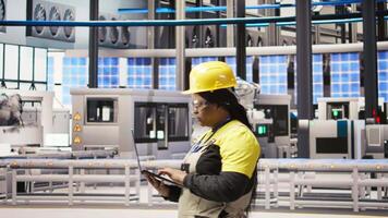Smart factory engineer using laptop to implement automated workflows and control systems, computerizing operations. Technician integrates sensors into production using notebook, camera A video
