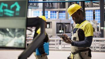 Engineer oversees solar panel production lines equipment using tablet app. Worker maintains photovoltaic assembly systems in automated industry 4.0 factory using digital device application, camera A video