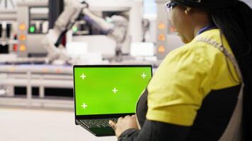 Engineer in photovoltaics factory using chroma key laptop to look at system performance metrics. Worker in industry 4.0 plant using green screen mockup notebook to track energy production, camera B video