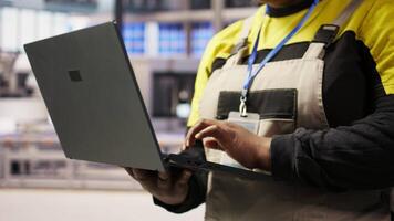 Industrial plant expert overseeing installation process using laptop, troubleshooting errors. Manufacturing facility employee calibrating automated robotic arms using notebook, camera A closeup video