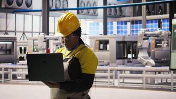 Portrait of smiling solar panels factory engineer analyzing data on laptop to predict gear failures. Happy photovoltaics plant employee using notebook, following maintenance procedures, camera A video