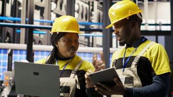 Engineering team working together in industry 4.0 plant to diagnose malfunctions. Teamworking factory colleagues coordinating repair tasks on manufacturing assembly lines, camera B video