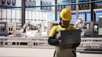 Smiling smart factory specialist testing automated systems to ensure reliability. Happy engineer in industry 4.0 industrial plant identifying bottlenecks and optimizing gear based on data, camera A video