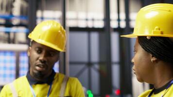 Manager overseeing work done by engineer in smart factory, ensuring quality control during manufacturing. Team leader supervising employee monitoring automated conveyor systems, camera B video
