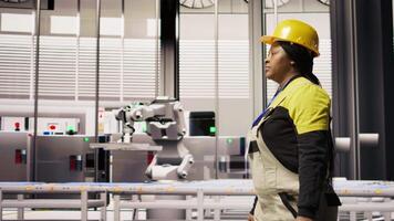 Engineer in smart factory overseeing robotic assembly lines, ensuring quality control in manufacturing process. Worker monitoring automated conveyor systems, doing maintenance, camera A video