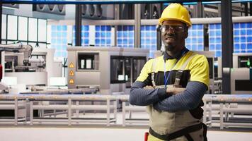 Portrait of technician overseeing solar panel production lines equipment. African American man maintaining photovoltaic assembly systems in automated industry 4.0 factory using computer, camera A video