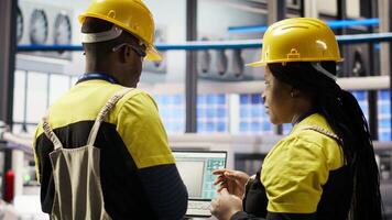 Smart solar panels factory engineering team using laptop to oversee production lines. Teamworking industry 4.0 plant coworkers ensure machinery operates at optimal efficiency using notebook, camera B video